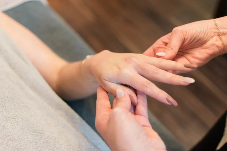 Beauty therapist massaging a client's hand during a treatment