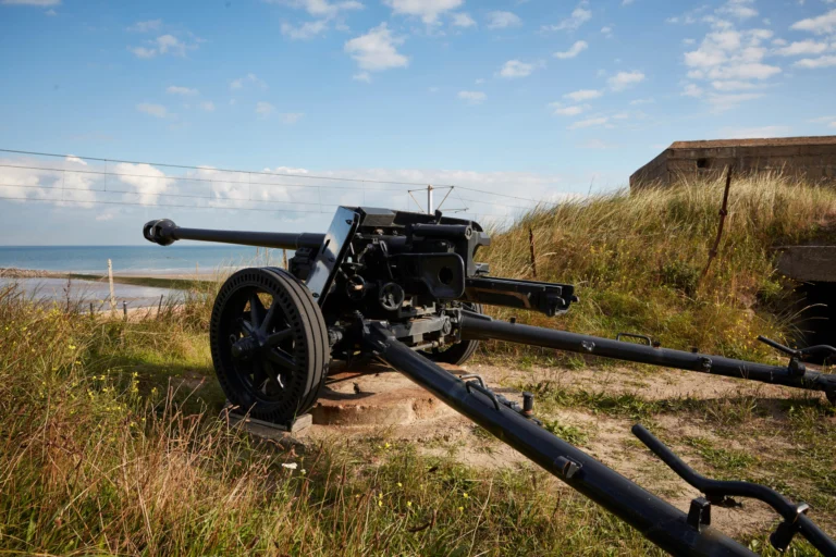 A Second World War anti-tank gun positioned in the dune grass, with the sea and a bunker behind