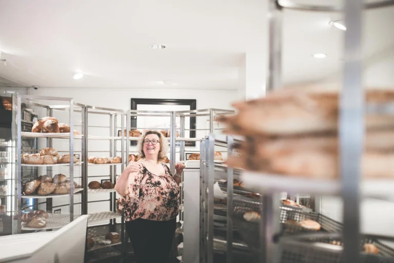 Inside the bakery shop, with racks of bread and pastries and a member of staff standing at the back