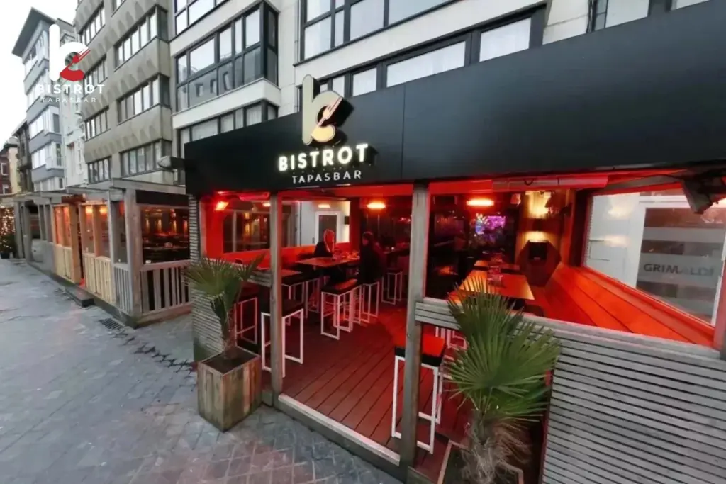 Bistrot's black frontage with the Bistrot Tapasbar sign above a red-lit covered terrace with high tables and potted palms