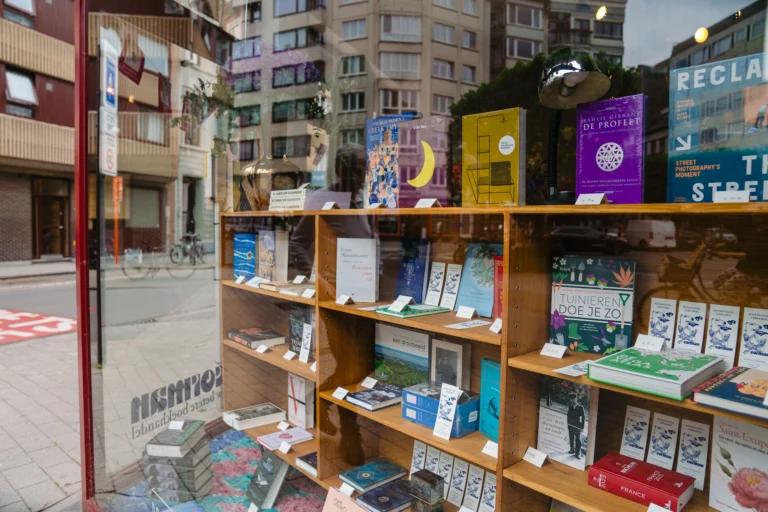 Wooden shelves of books in the shop window, seen from inside with the street and apartment blocks beyond