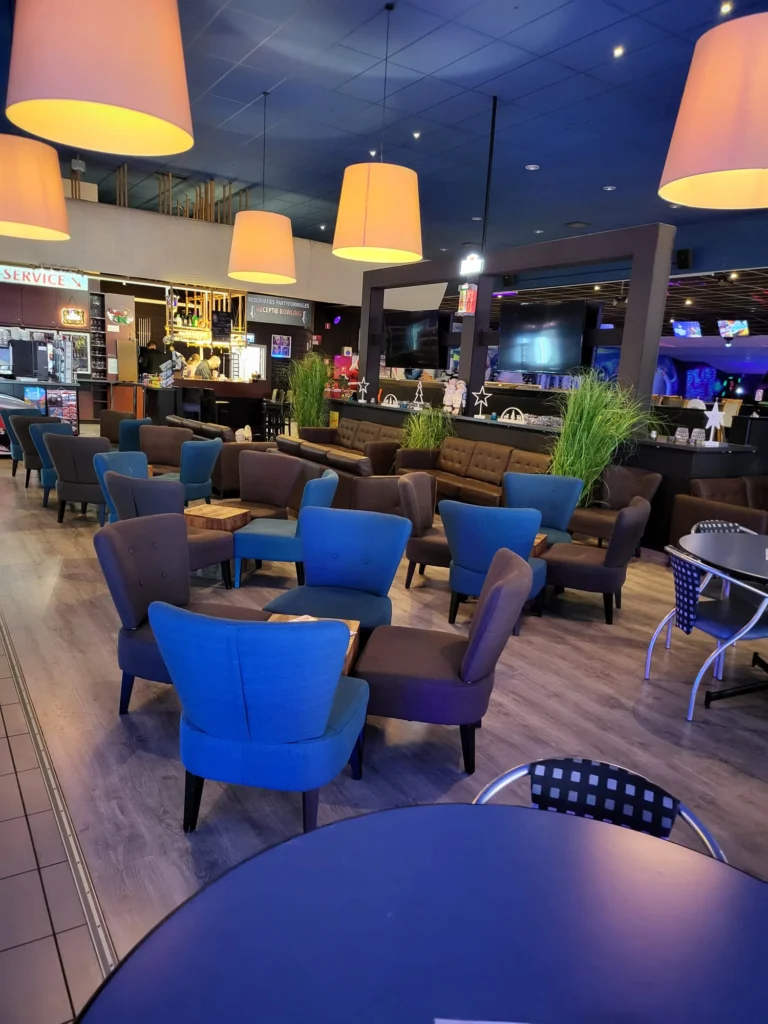Lounge area with blue and brown armchairs, large pendant lamps and the bar in the background
