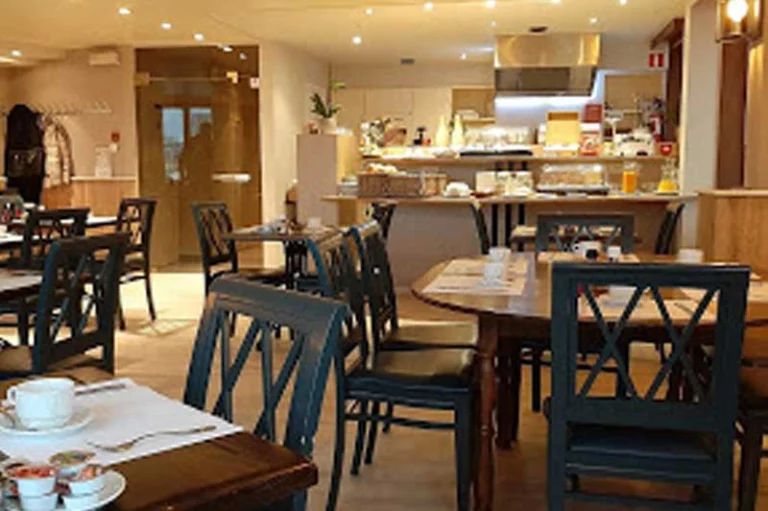 Breakfast room with wooden tables, dark blue chairs and a breakfast counter at the back