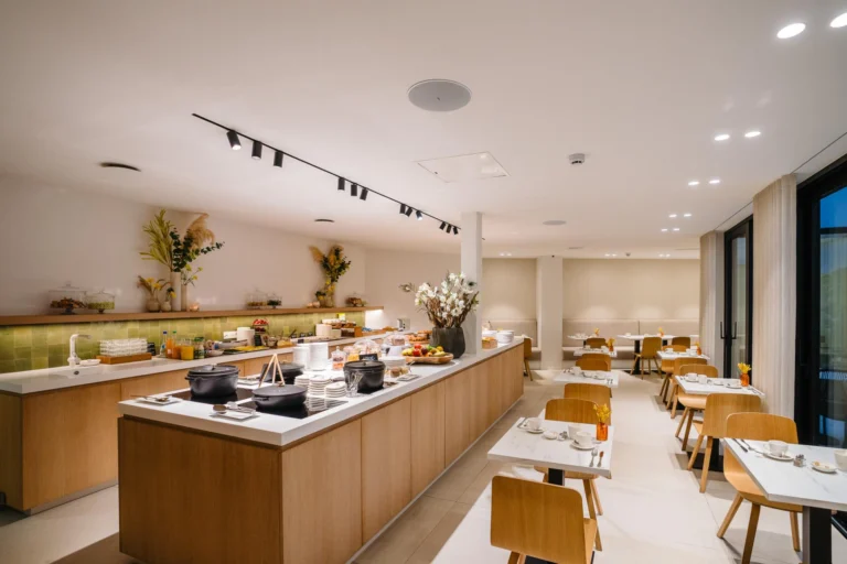 Breakfast room with a long wooden buffet counter, dried flower arrangements and small white tables