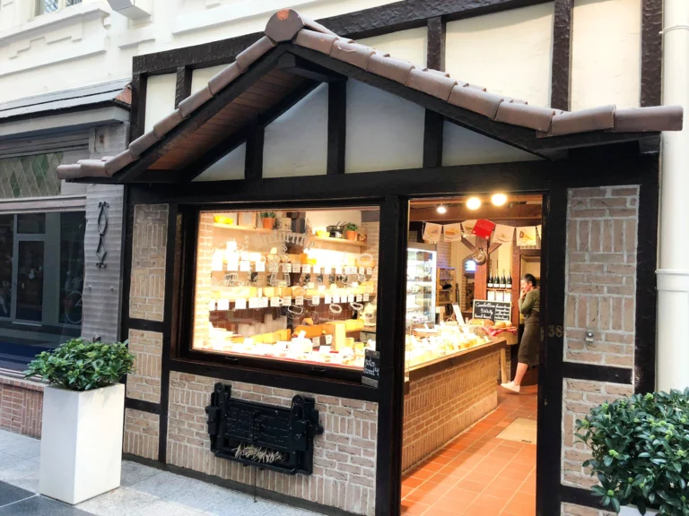 Bretoentje's half-timbered shopfront with a small tiled roof inside the covered James Ensorgalerij, its window lit up with cheeses