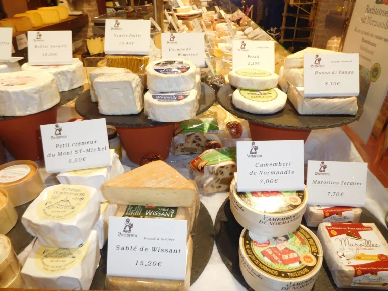 Close-up of French soft cheeses such as Camembert de Normandie, Petit crémeux du Mont Saint-Michel and Maroilles with handwritten price cards