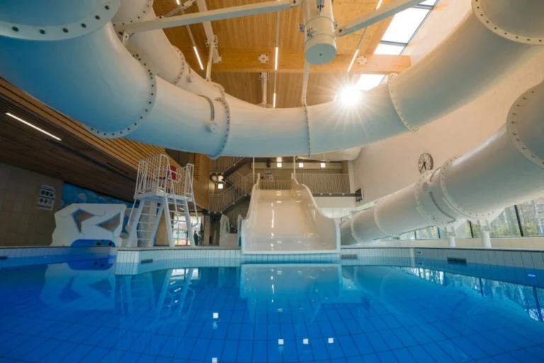 Leisure pool with a lifeguard chair, a wide white slide and large tube slides overhead