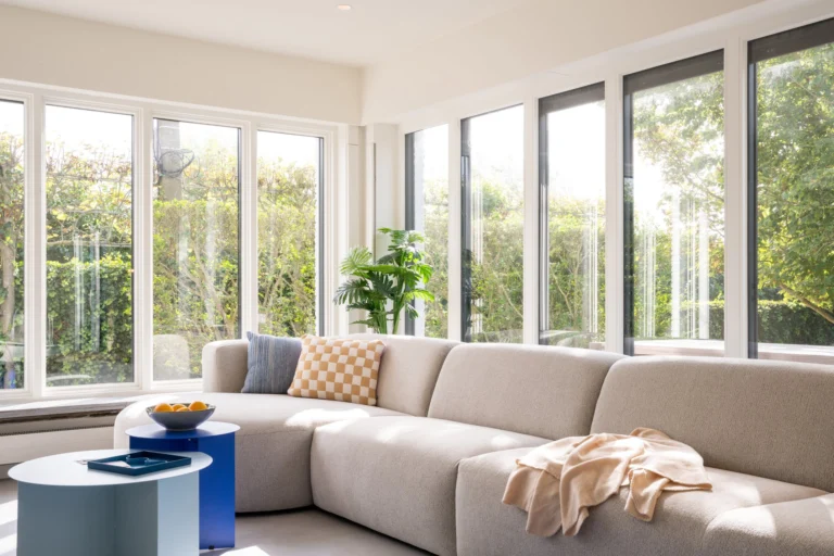 Bright garden room with a large corner sofa and floor-to-ceiling windows onto greenery