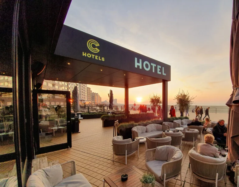 Covered terrace of Hotel Andromeda on the promenade at sunset, with lounge chairs facing the beach