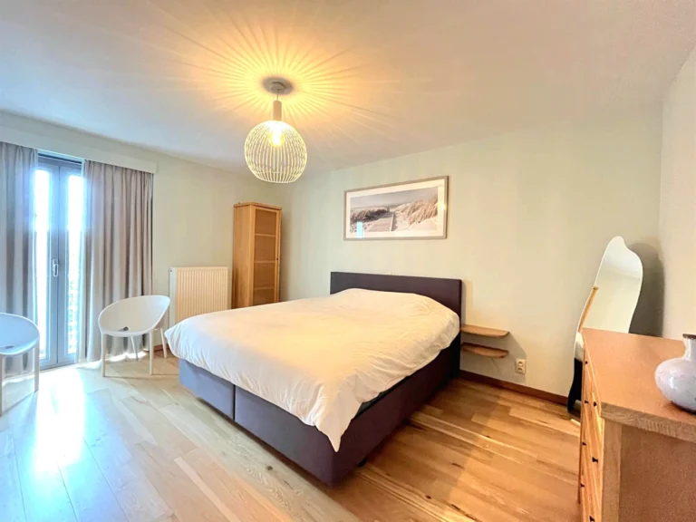 Double bedroom with oak flooring, a wire pendant lamp, a pine wardrobe and doors to a balcony