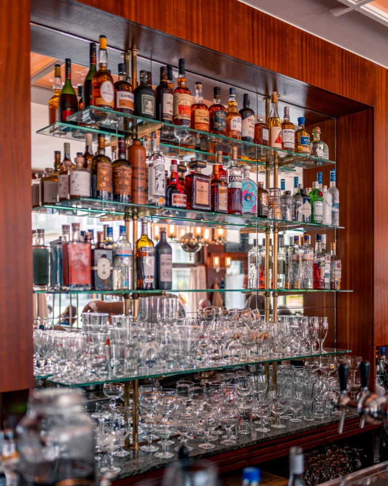 The wood-framed back bar of the café with glass shelves of bottles and glasses