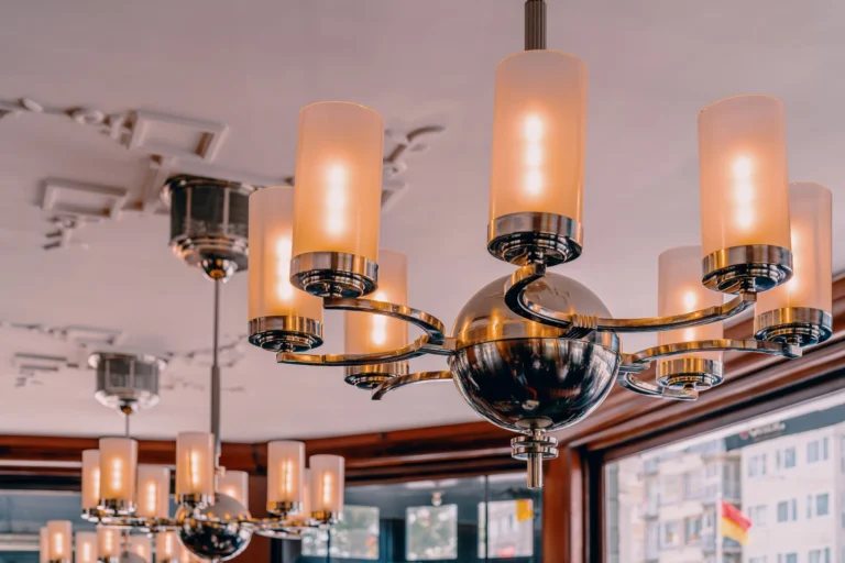 Art deco chandeliers with frosted glass shades hanging from the ceiling of the café, with a window to the street behind