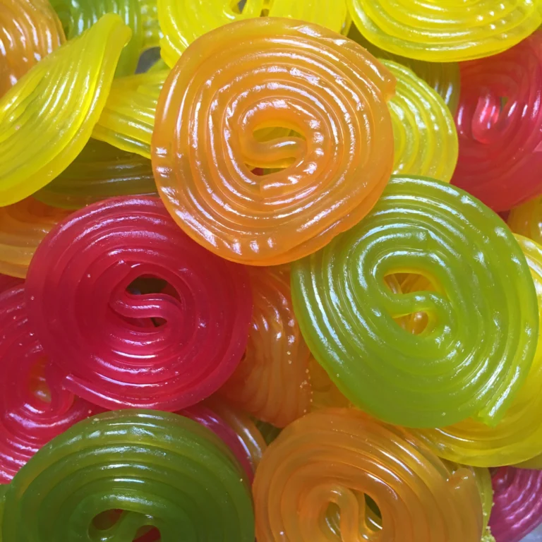 Close-up of glossy coiled fruit liquorice wheels in yellow, green, pink and orange