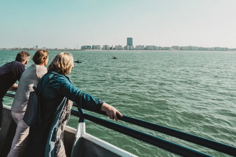 Passengers leaning on the boat's rail, looking across the North Sea at the Ostend skyline