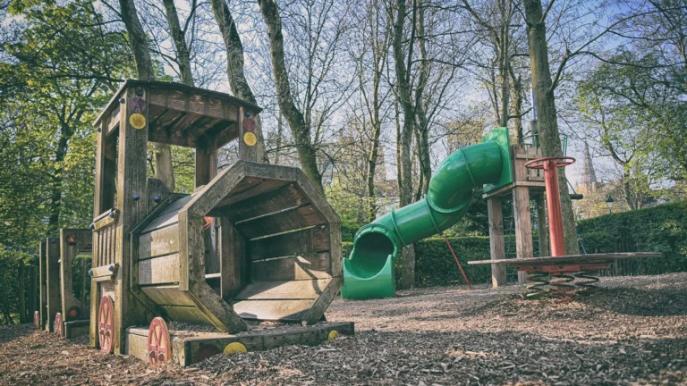 Wooden train climbing frame and green tube slide in the playground beside the minigolf
