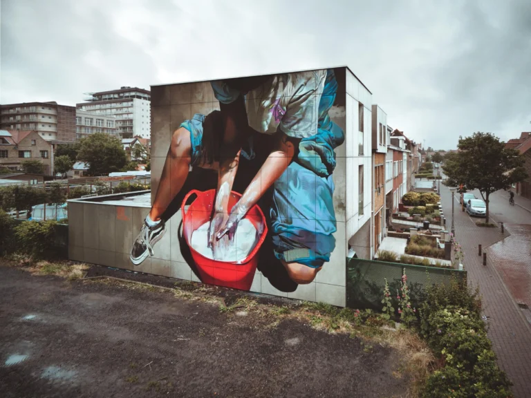 Photorealistic mural by Case Maclaim of hands washing in a red bucket, painted on the side of a house