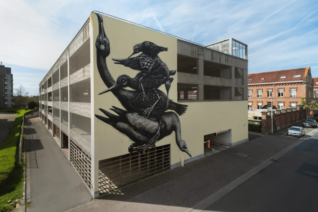 Large black-and-white mural of stacked wading birds by ROA on the end wall of a multi-storey car park