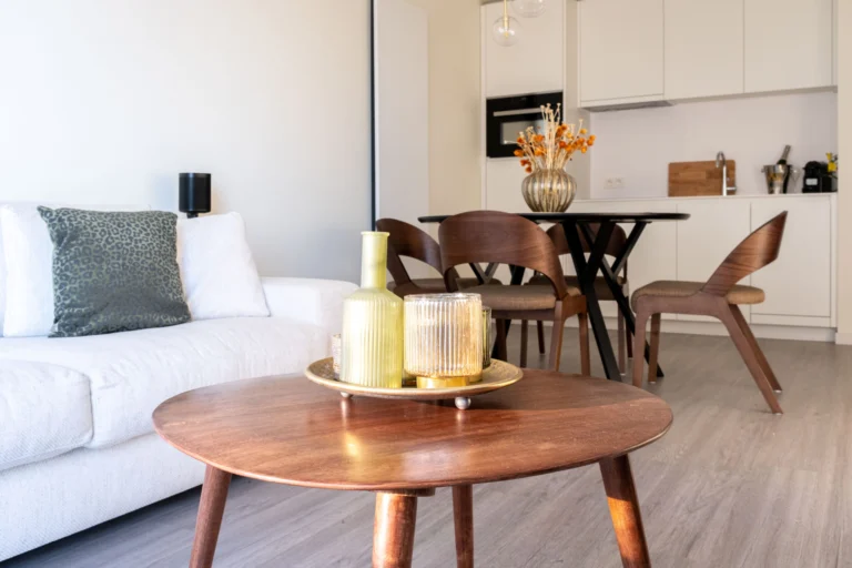 Lounge with a round wooden coffee table, opening onto the dining area and white kitchen