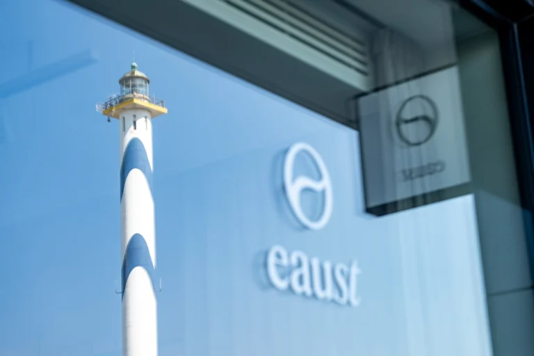 The Lange Nelle lighthouse reflected in the restaurant window beside the white EAUst logo