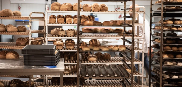 Metal racks of freshly baked loaves and bread rolls in the bakery