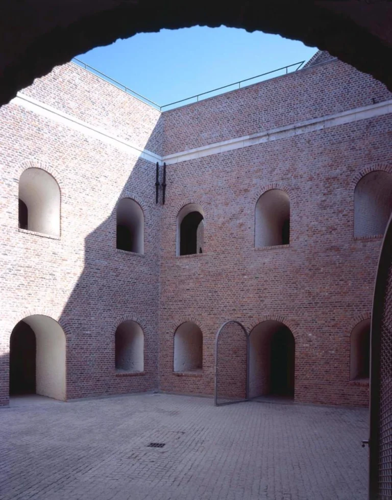 The empty brick inner courtyard of Fort Napoleon with arched doorways and windows under a blue sky