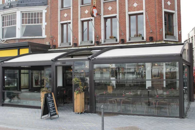 Red-brick facade of Hotel Rubens with a glazed, awning-covered brasserie terrace at street level