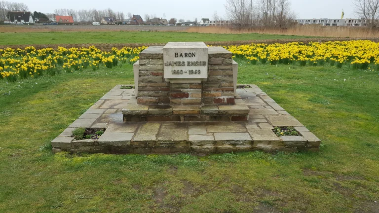 James Ensor's block-shaped brick and stone tomb inscribed Baron James Ensor 1860–1949, with yellow daffodils behind