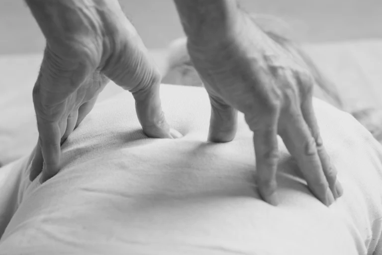 Black-and-white close-up of a therapist's hands pressing on a client's clothed back
