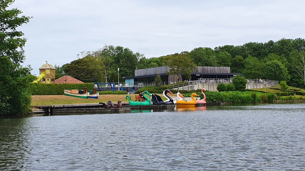 Lake in the Maria Hendrikapark with colourful swan pedal boats moored in front of the Koninginnehof pavilion