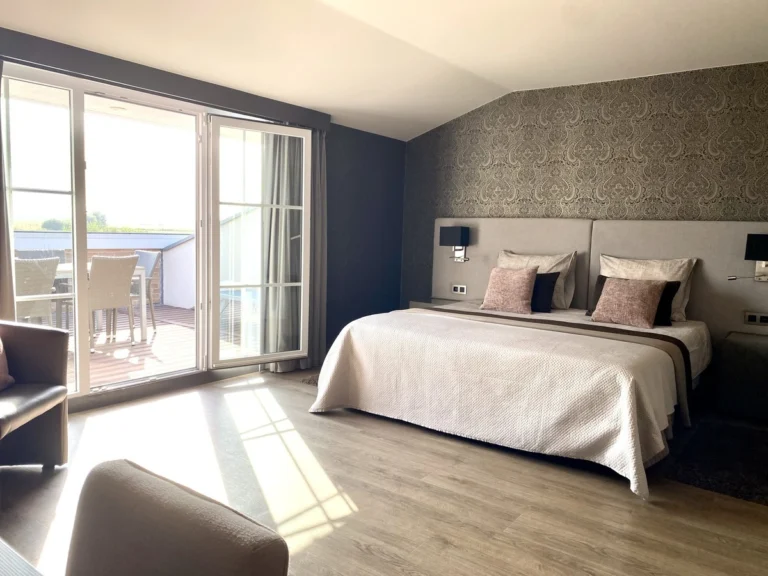 Bright double room with grey patterned wallpaper and glass doors opening onto a private terrace