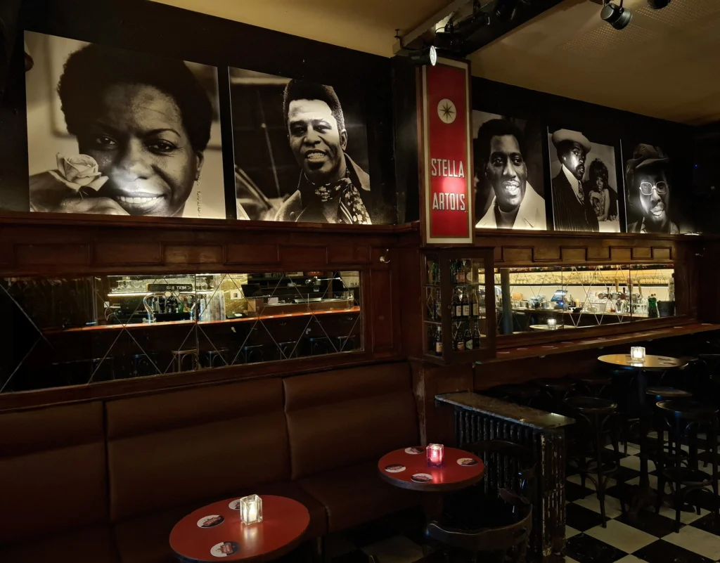 Dark wood interior of Lafayette with banquettes, candlelit tables and large black-and-white portraits of soul musicians above the bar