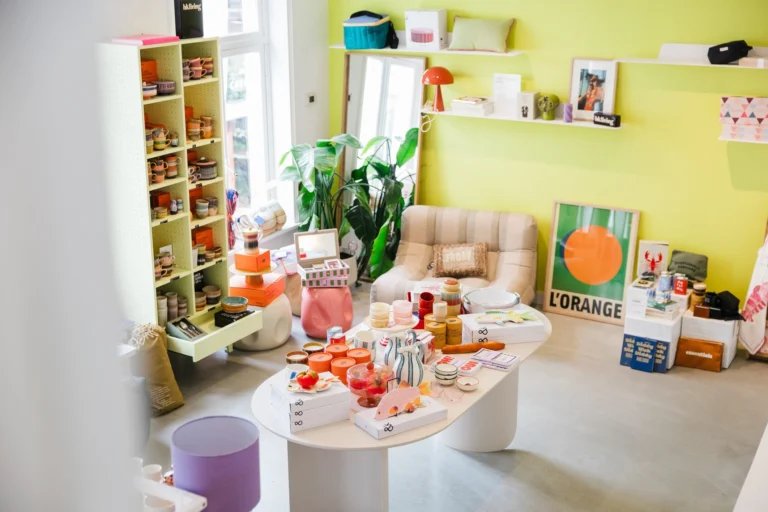 Bright decoration corner with a lime-yellow wall, shelves of homeware, a low white table of gifts and a cream armchair