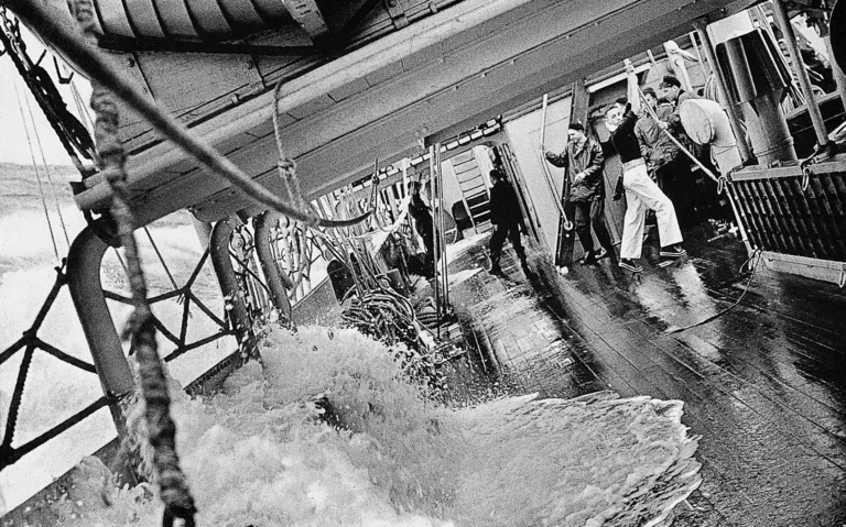 Black-and-white archive photo of crew on the Mercator's deck as waves wash aboard during a 1936 Atlantic storm