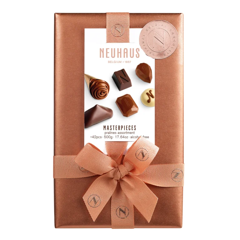 A Neuhaus Masterpieces praline ballotin wrapped in copper paper with a large ribbon bow, on a white background