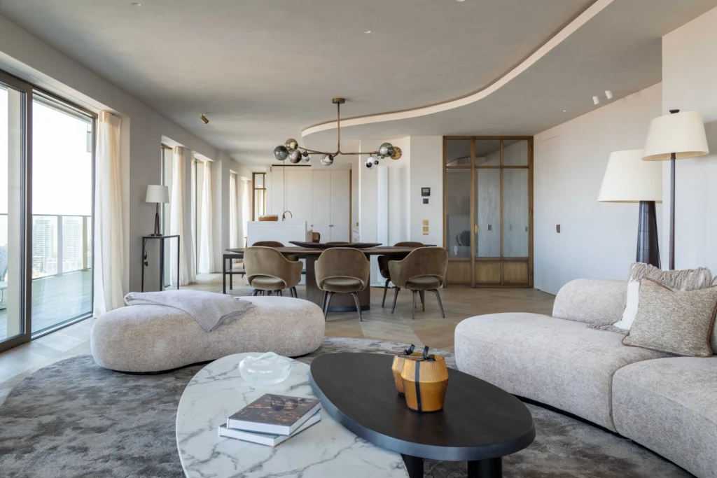 Spacious living room with curved cream sofas, a marble coffee table and floor-to-ceiling windows