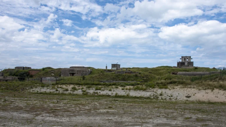Grassy dune landscape on the East Bank dotted with old concrete bunkers under a cloudy sky