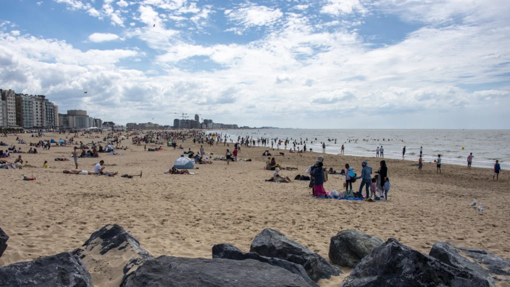 Busy sandy beach on a summer day, with seafront apartment blocks stretching along the coast