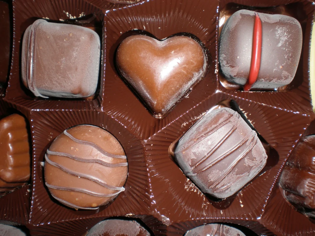 A box of assorted Belgian pralines in a moulded tray, including a heart-shaped chocolate, in dark and milk chocolate