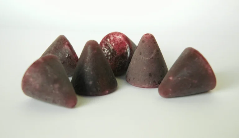 Six cuberdons, the purple cone-shaped Belgian sweets, on a white surface