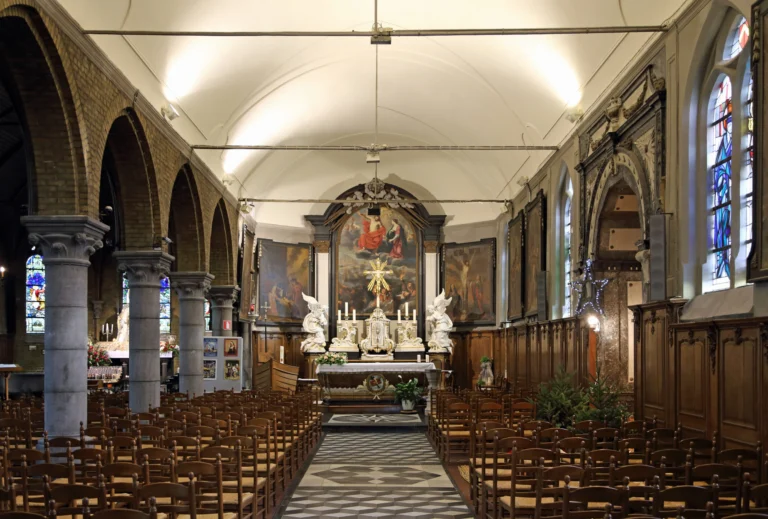 Nave with rows of chairs, oak panelling and round columns leading to the high altar and its large painted altarpiece