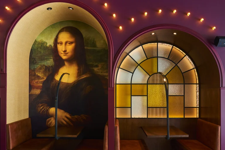 Two arched booths with a string of lights, one painted with the Mona Lisa and one with a stained-glass window