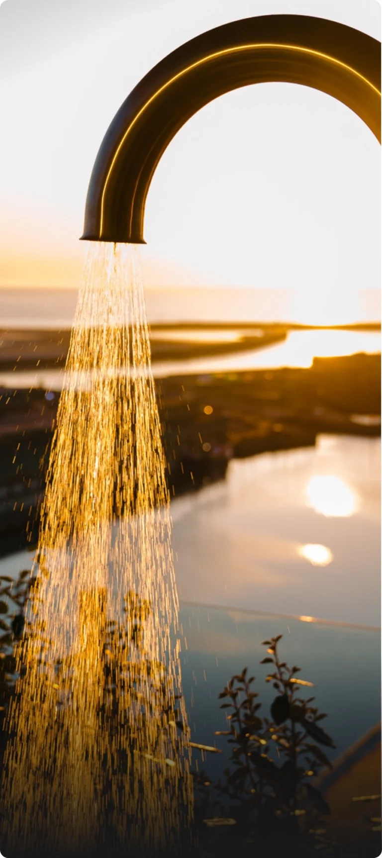 Arched outdoor shower running against a sunset over the harbour