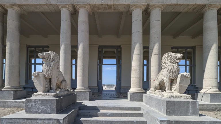 Two stone lion statues guarding the steps of the restored colonnade