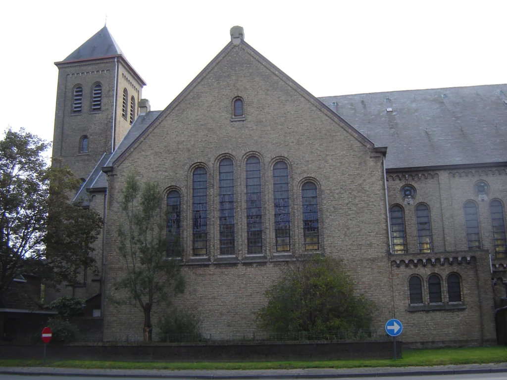 The brick Sint-Jan-Baptistkerk in Ostend, a parish church with a tall spire, seen from the street