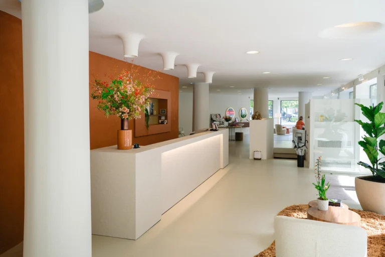 White reception desk with flowers in a bright salon with white columns and plants