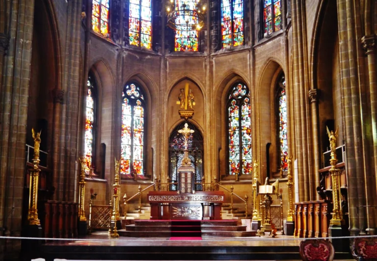 Choir and high altar framed by colourful stained-glass windows in the church's apse