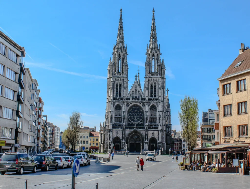 Neo-Gothic west front of the Church of St Peter and St Paul with twin spires above a square under blue sky