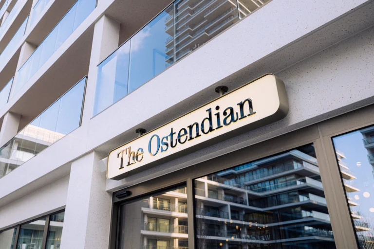 Modern building with an illuminated The Ostendian sign above its glazed ground-floor entrance