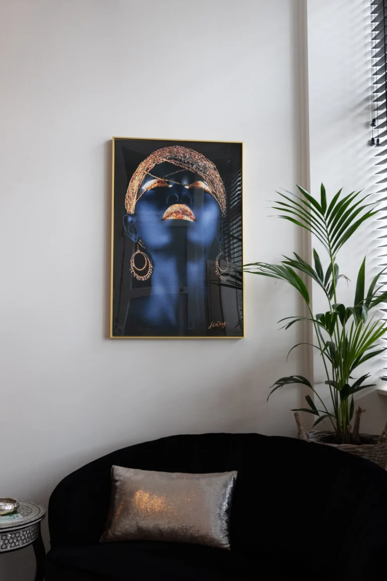 Waiting corner with a black velvet sofa, a potted palm and a framed portrait on a white wall
