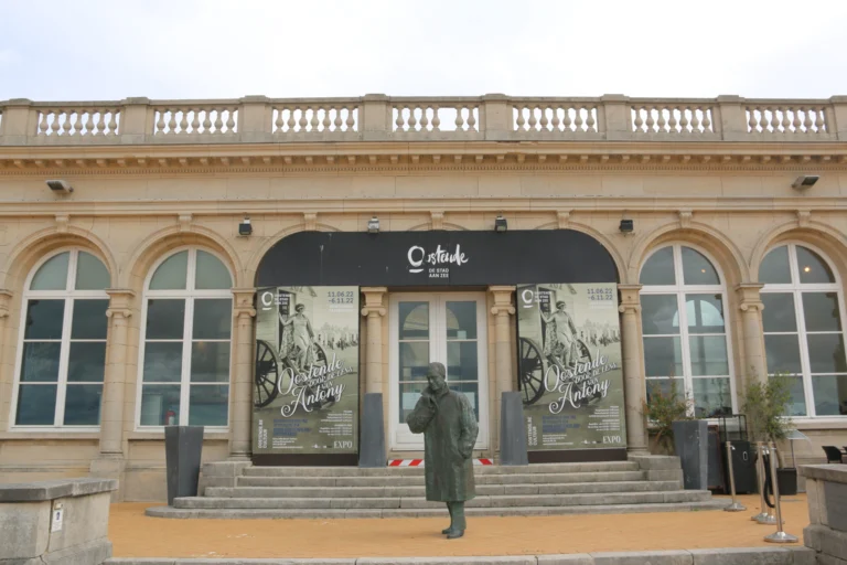 Bronze statue of King Baudouin in front of the arched seafront entrance of the Venetian Galleries, below a stone balustrade